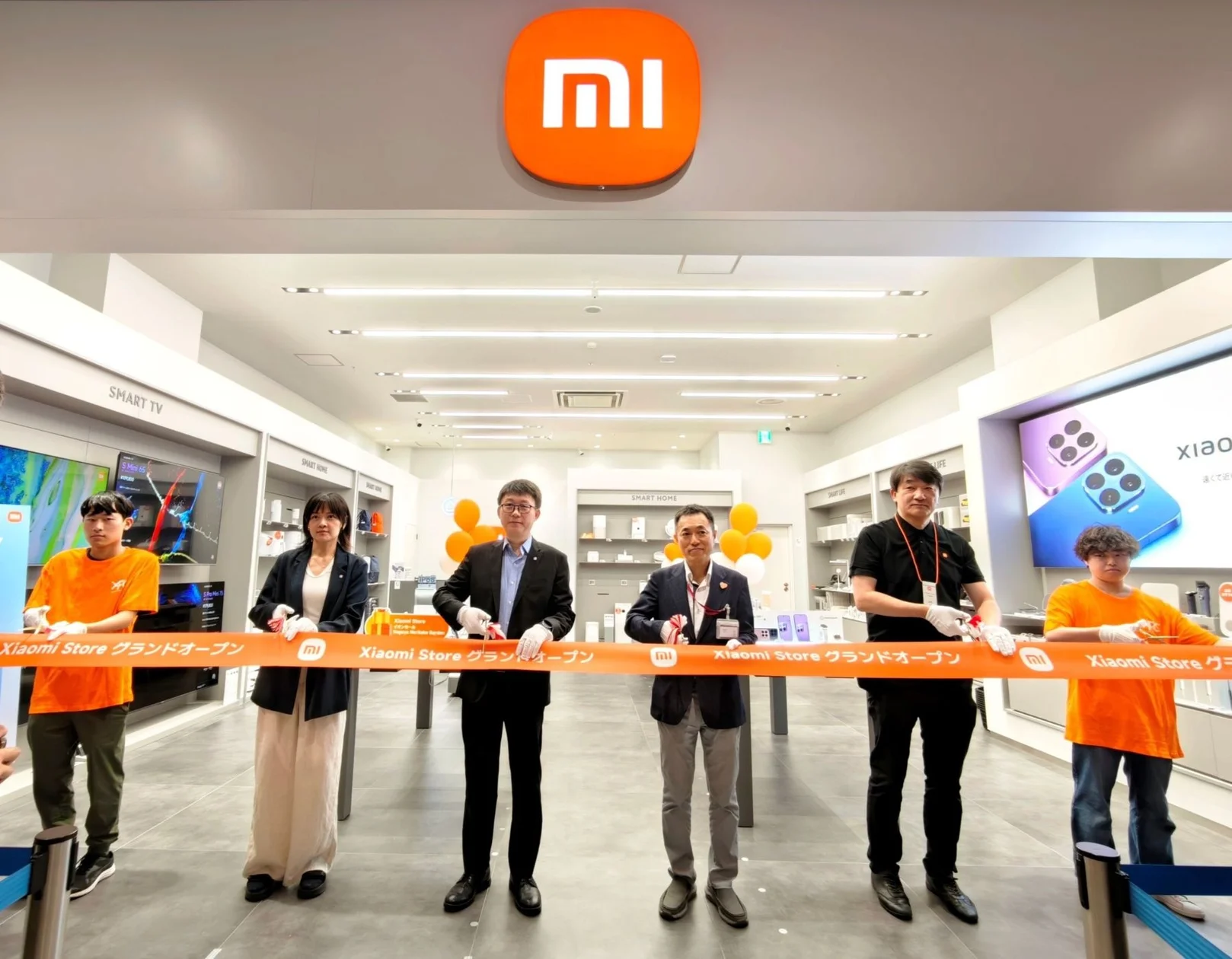 Xiaomi Store イオンモール Nagoya Noritake Garden店のオープンセレモニーにて、登壇する呂暁露氏と原田義夫氏、そして1日店長を務める山根康宏氏が並んでいる様子。